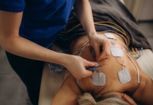 Patient receiving electrotherapy on lower back to reduce inflammation and support tissue healing
