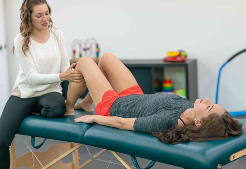 Physiotherapist treating a patient lying on a table for pelvic health.