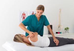Physiotherapist examining a patient on a treatment table with anatomical charts in the background.