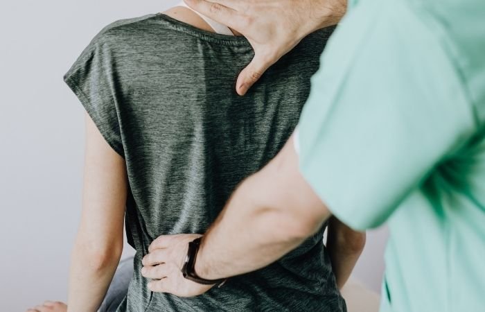 Physiotherapist palpating a patient's lower back to assess a possible cause of sciatica